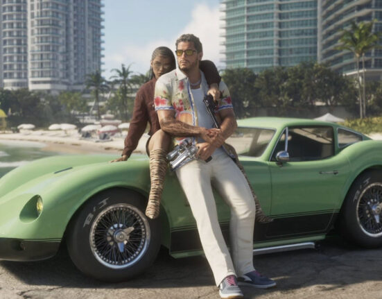 Nova imagem de GTA 6 mostrando um homem e uma mulher encostados em um carro com Vice City ao fundo.