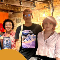 Grupo de artistas de quadrinhos em frente de uma livraria