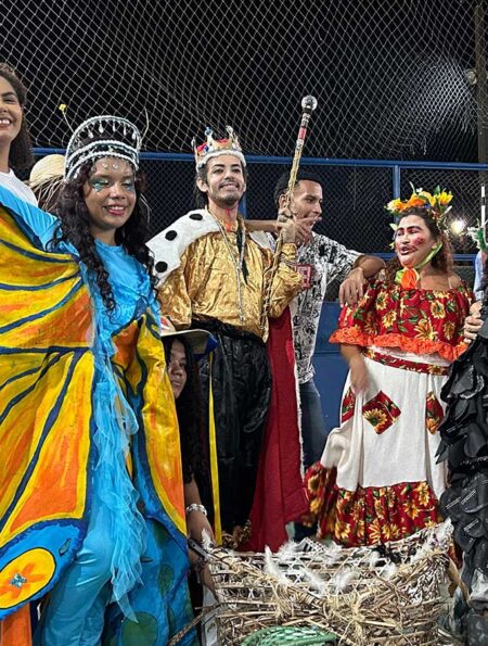 Grupo de teatro popular Pássaro Urubu com fantasias coloridas e maracas, prontos para apresentação em Belém.