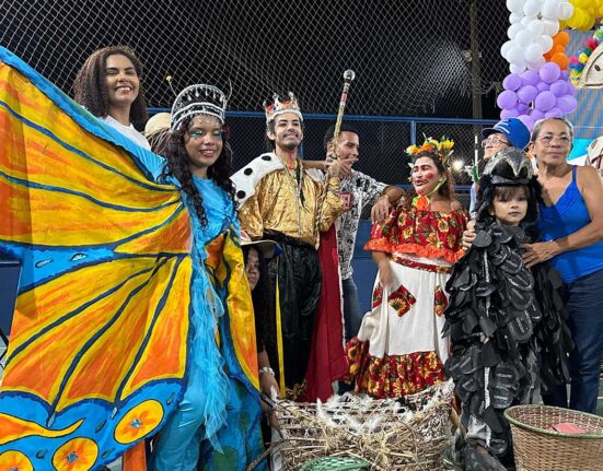Grupo de teatro popular Pássaro Urubu com fantasias coloridas e maracas, prontos para apresentação em Belém.