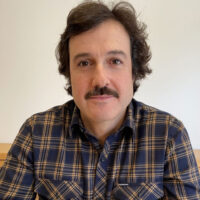 Fotografia em close do autor Bruno Gil Gonzalez, um homem de traços expressivos, representando a nova voz da literatura dramática brasileira.